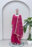 Mannequin wearing a magenta traditional outfit with a plant in the background