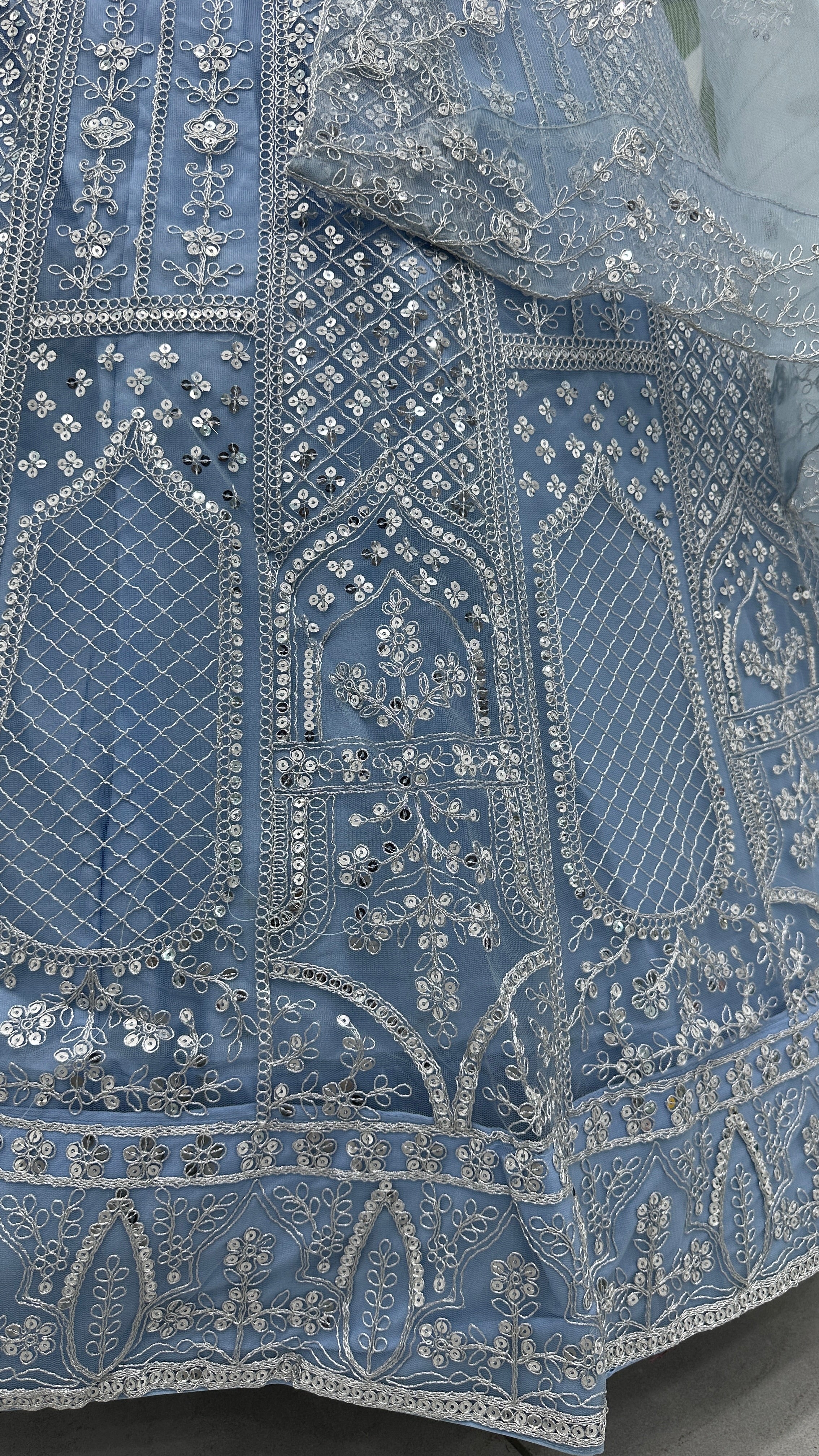 Close-up of intricately embroidered blue fabric with silver thread
