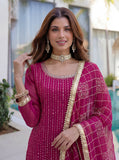 Woman wearing a pink traditional outfit with gold details outdoors.