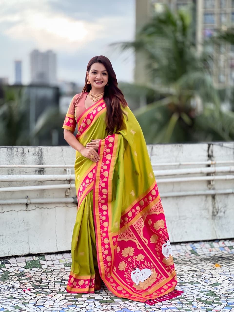 Woman wearing olive green Paithani silk saree with pink lotus zari border and traditional pallu