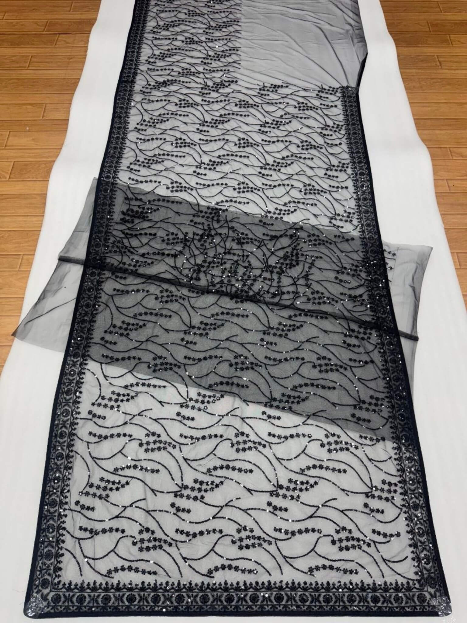 Detailed view of the sheer black net saree pallu decorated with intricate floral sequin patterns.