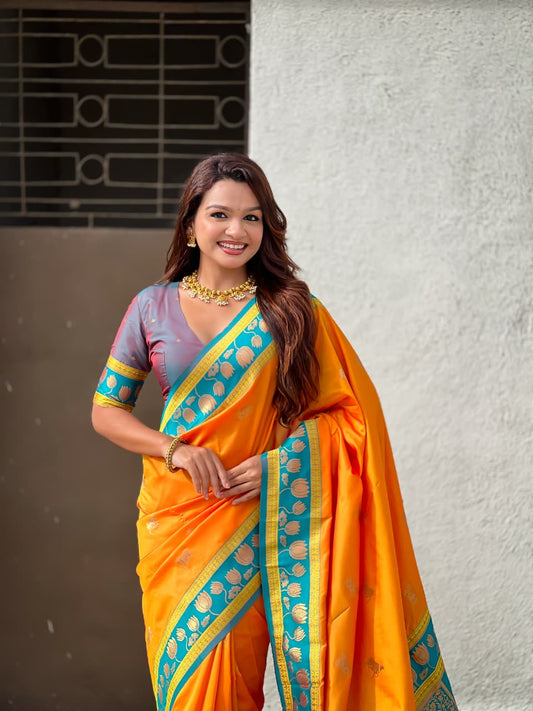 Festive wear orange Paithani silk saree with teal border, lotus artwork and luxurious ethnic styling.