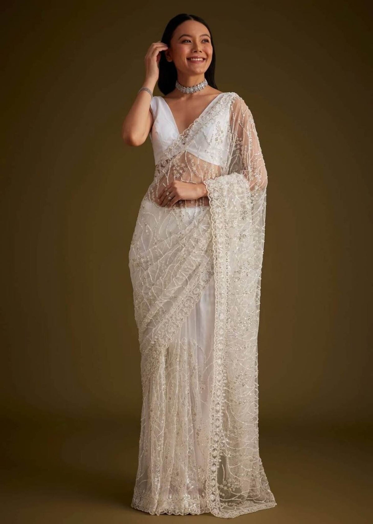 Ivory white net saree with heavy sequins and stone embroidery paired with matching sleeveless blouse.