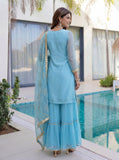 Woman in a light blue traditional outfit standing by a poolside.