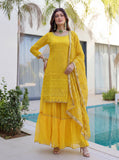 Women wearing yellow mirror work sharara set with embroidered dupatta near poolside