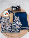 Navy blue embroidered fabric with pink floral patterns on a woven mat, accompanied by a sewing machine.